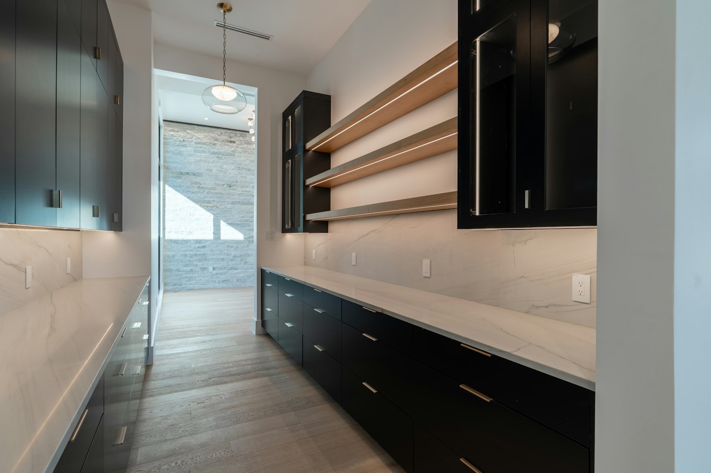 Long kitchen with dark lower cabinets and floating shelves