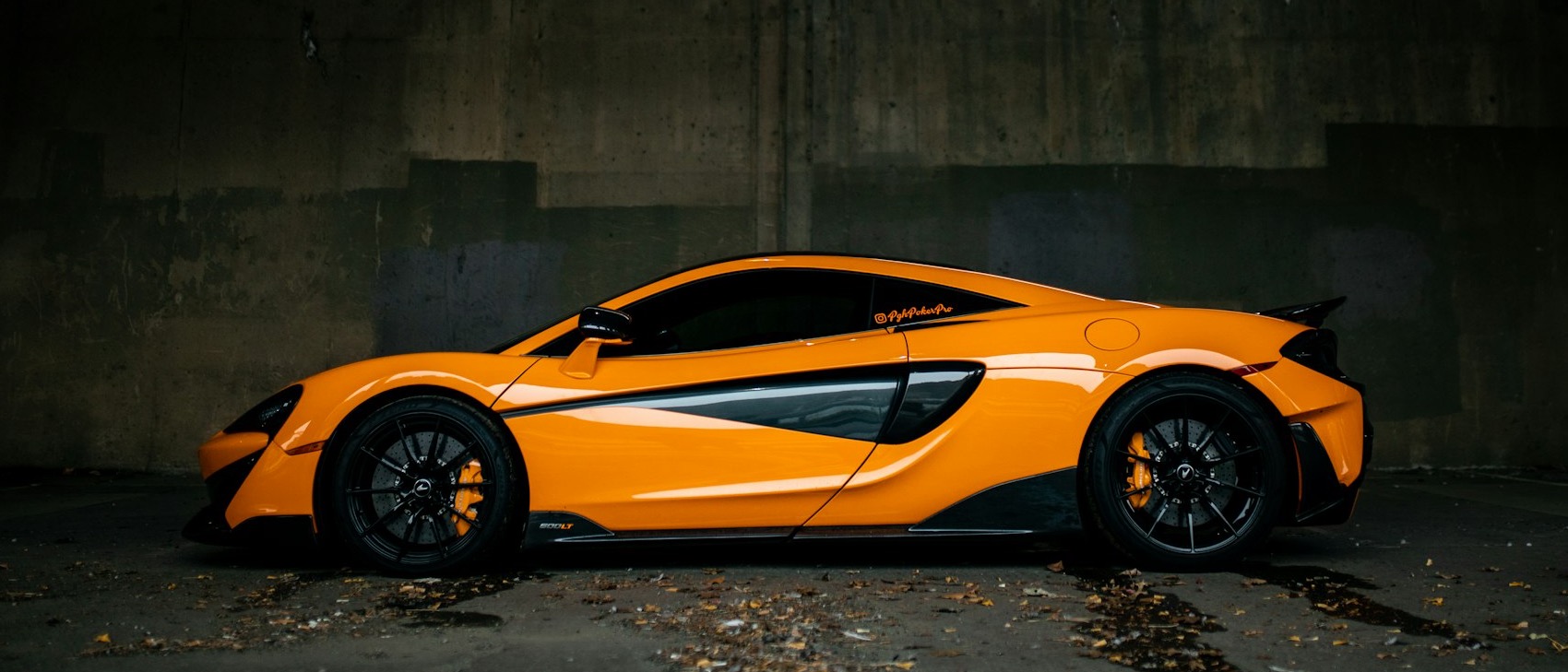 Orange supercar parked in a dark concrete hangar
