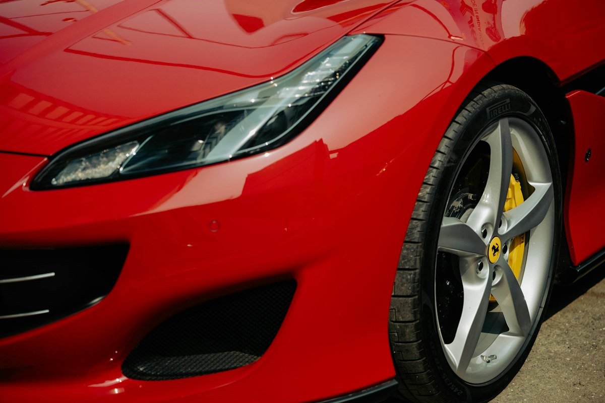 Glossy red front corner, headlight and wheel of a modern sports car