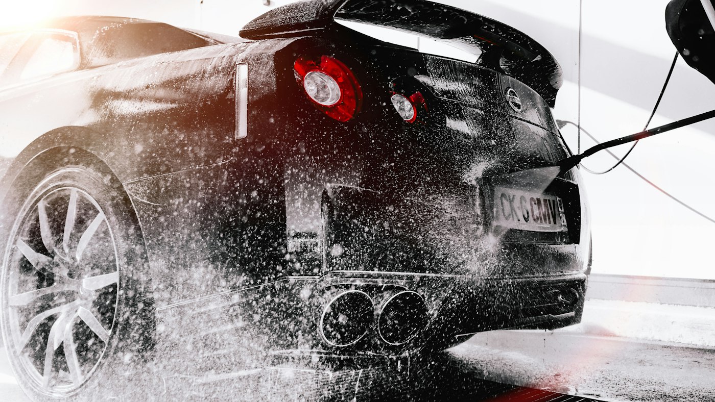 Foam wash spraying across a black sports car